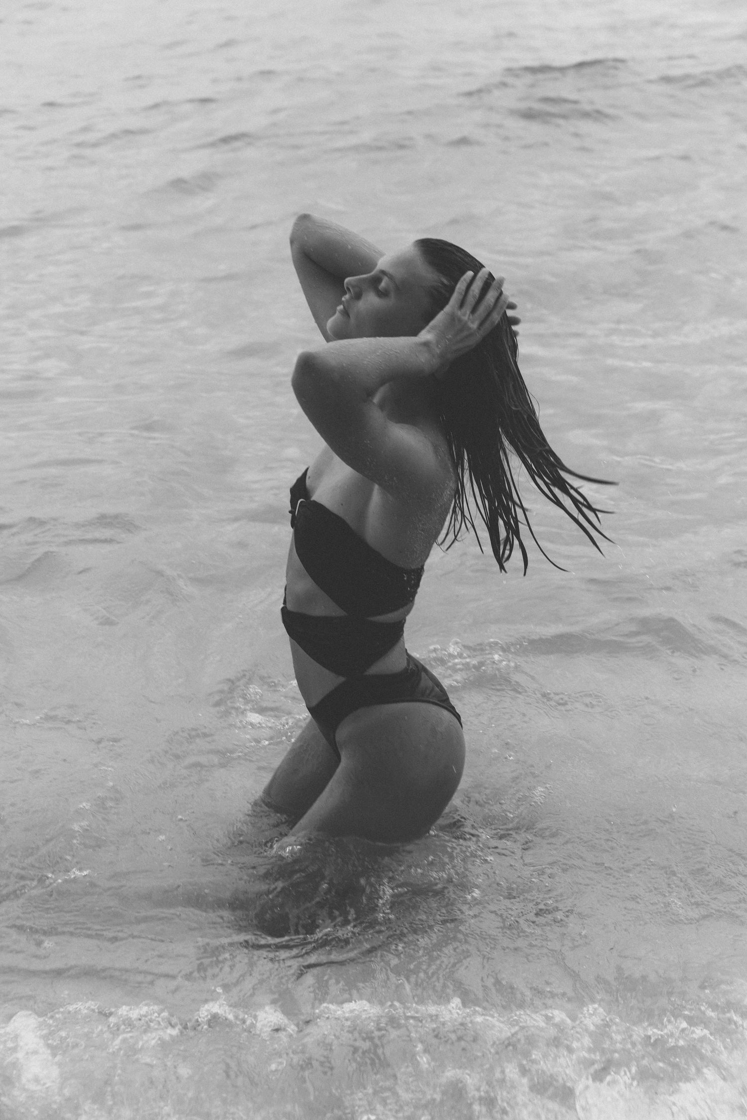 Black and white photo of a person in a swimsuit standing in water.