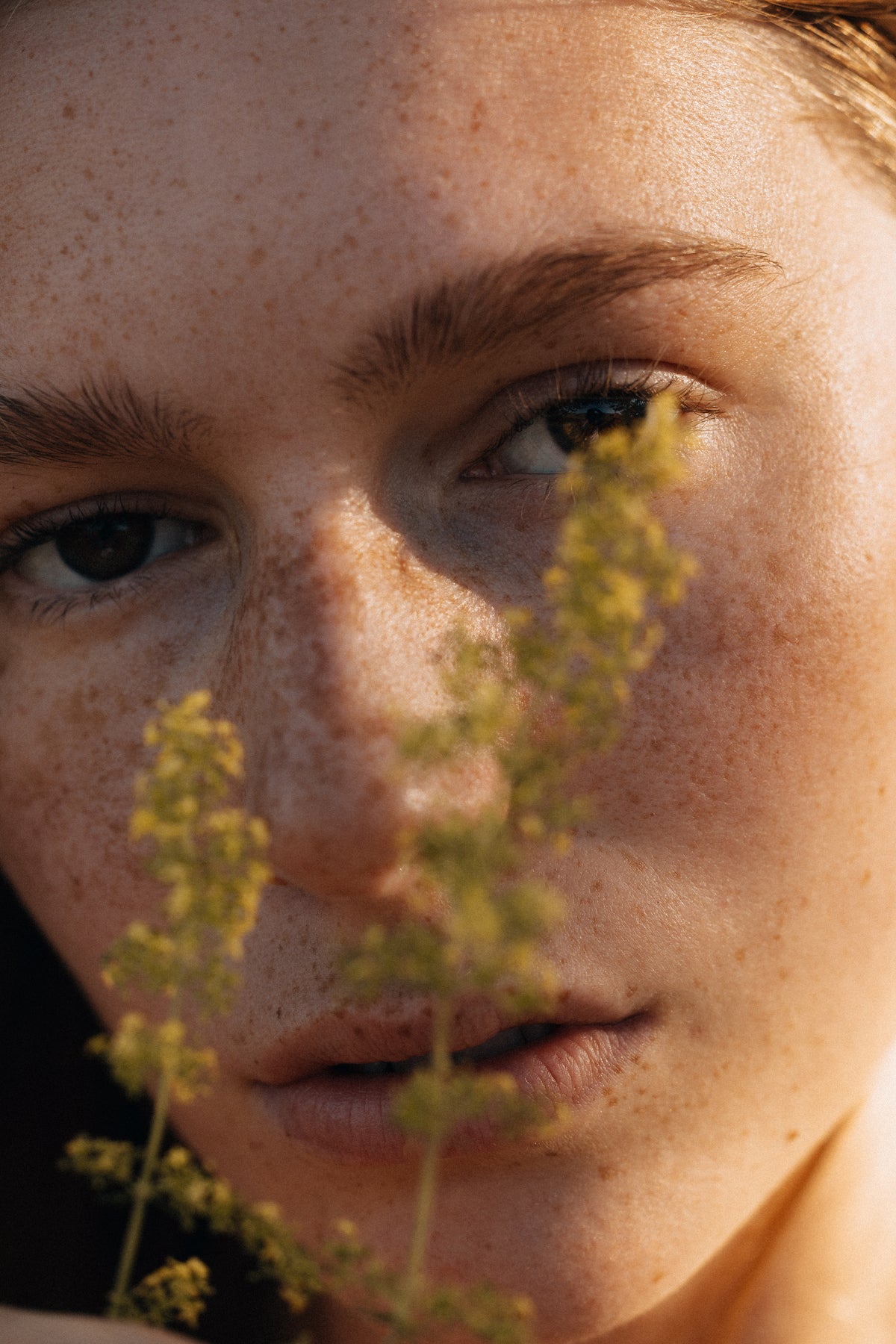 Close-up of a person with greenery in front of their face