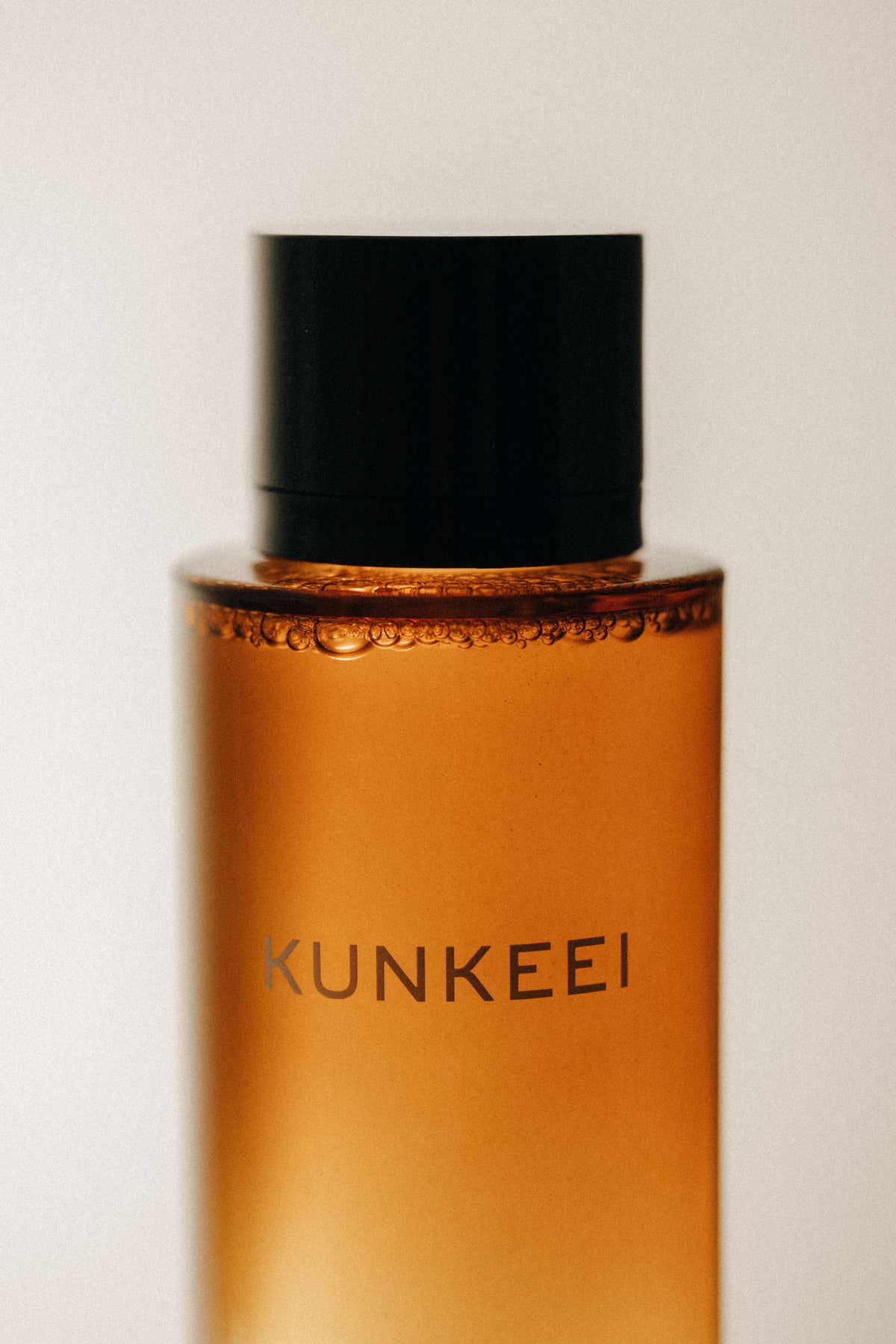 Orange bottle with black cap on a light gray background, featuring the brand 'KUNKEEI'.