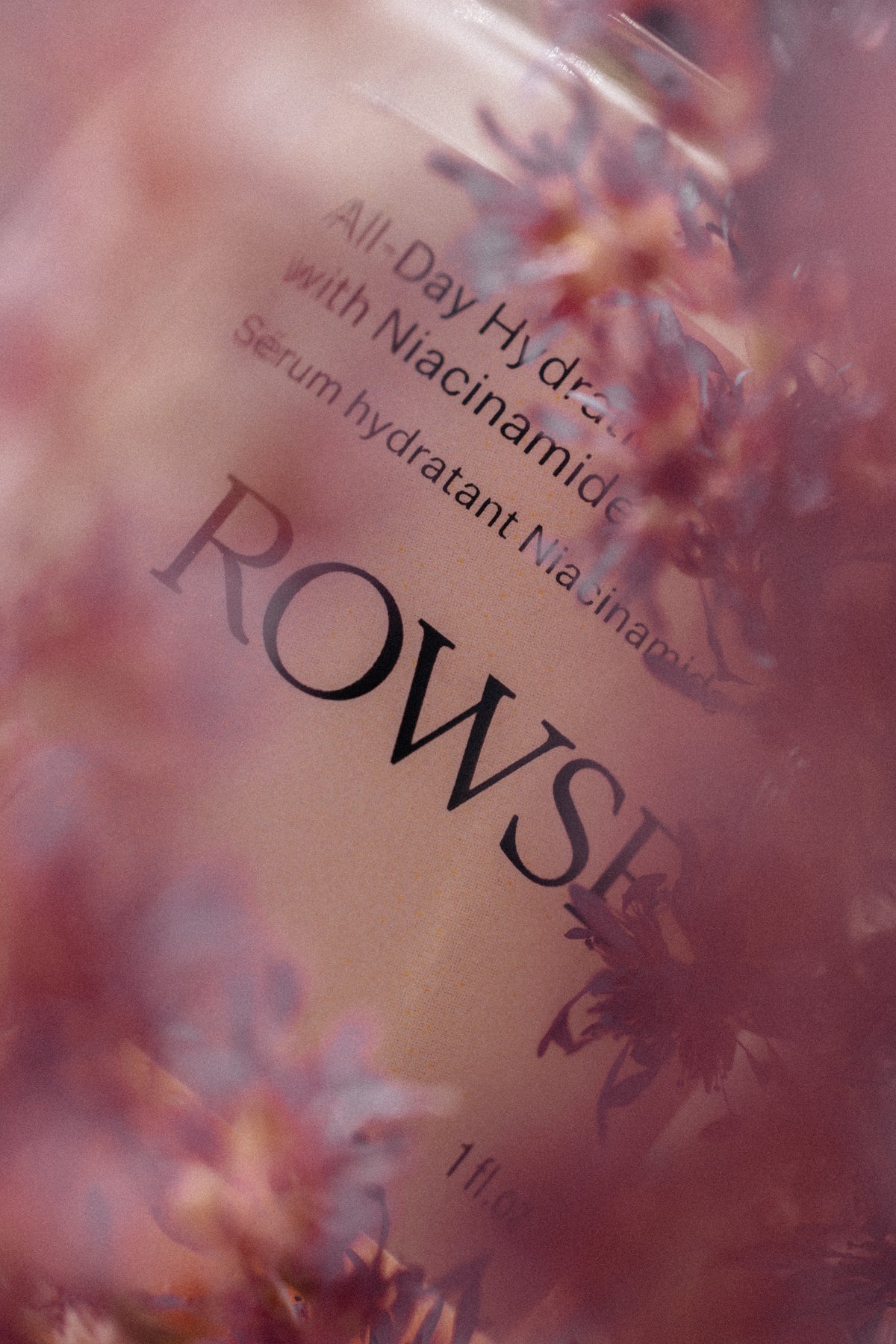 Skincare serum bottle labeled 'ROWS' with floral background